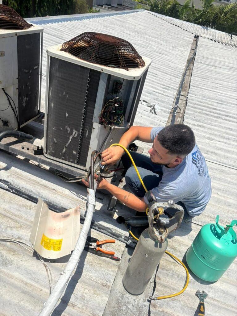 Técnico fazendo carga de gás em condensadora no telhado
