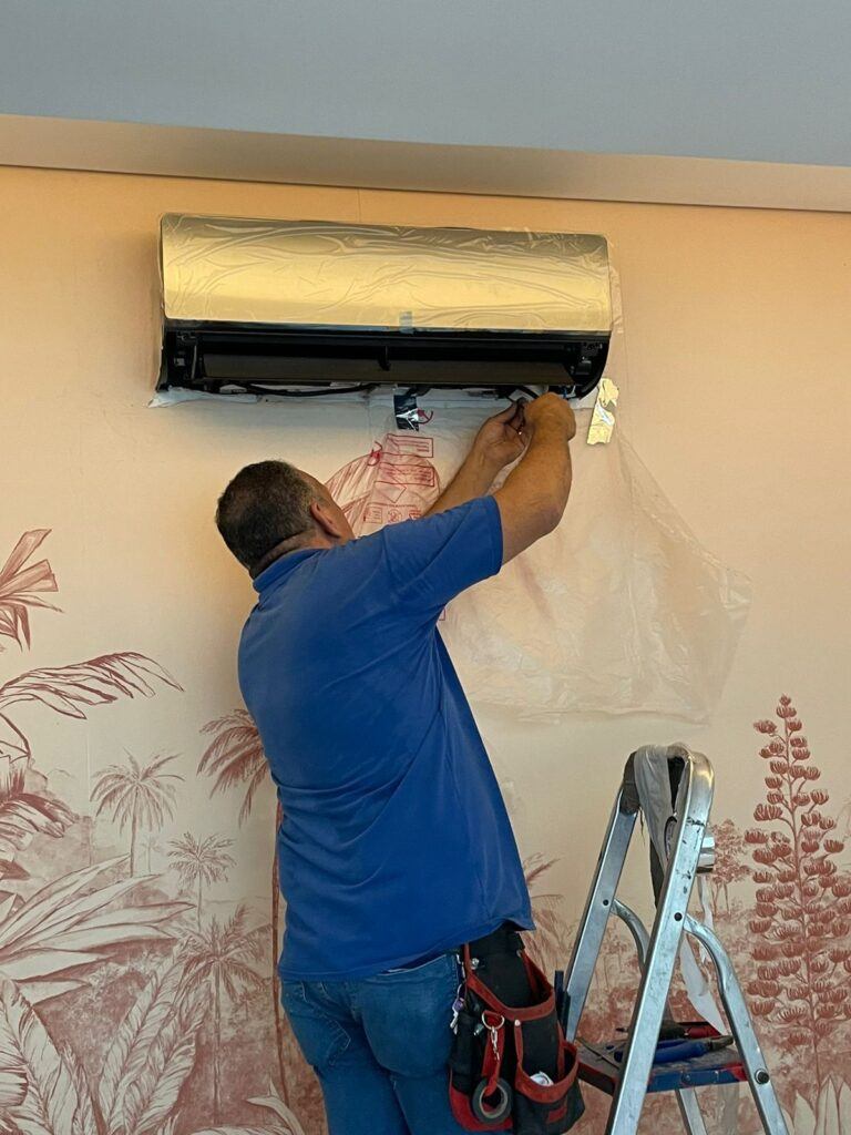 Técnico instalando evaporadora split com proteção plástica na parede decorada