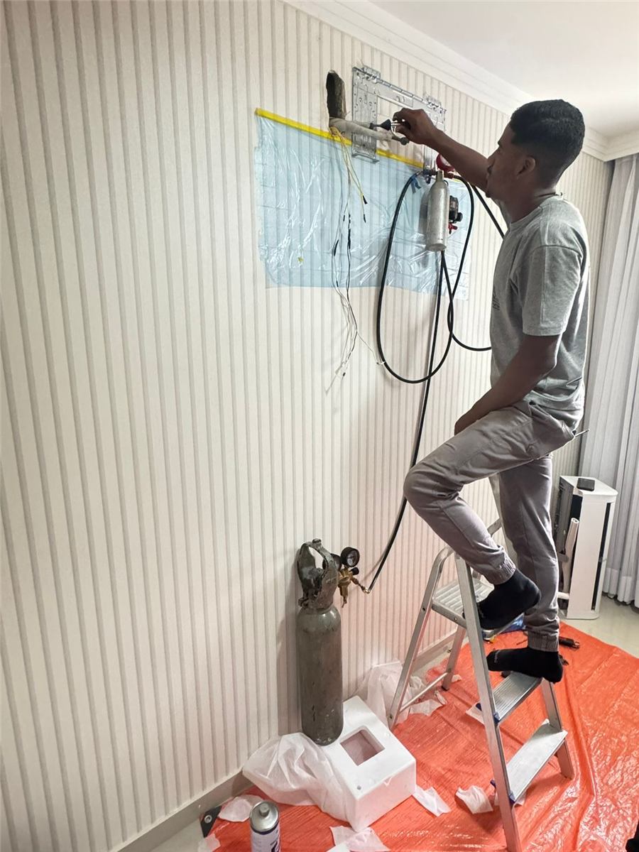 Técnico instalando suporte com plástico protegendo a parede e lona cobrindo o piso